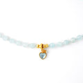 Close up detail of 18k gold plated S925 silver heart pendant with blue gemstone and pearl accent on Aquamarine beads
