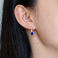 Natural deep blue oval Lapis Lazuli drop earring with CZ accents in S925 silver worn on model ear
