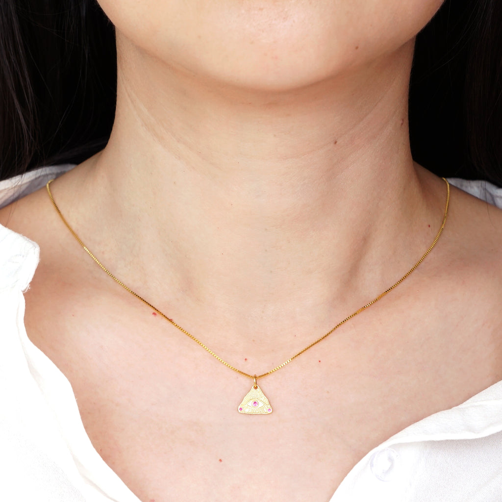 Gold textured Evil Eye triangle pendant necklace worn on model neck with white shirt

