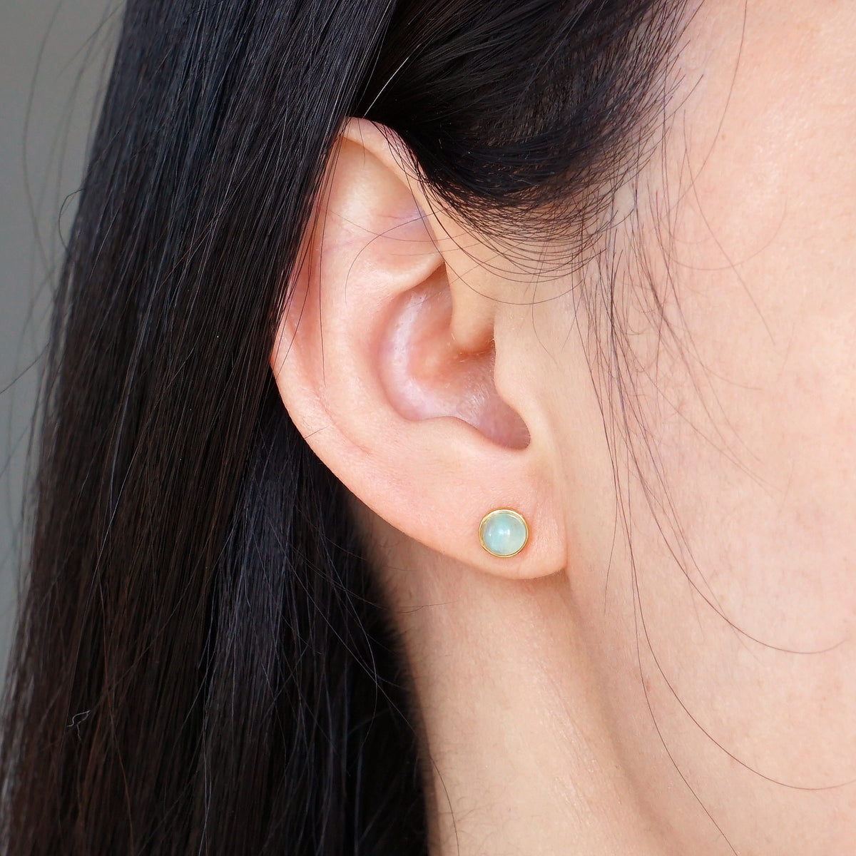 Natural light blue Aquamarine gold bezel stud earring worn on model ear

