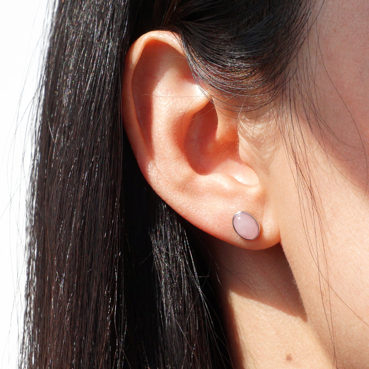 Natural Rose Quartz silver oval stud earrings worn on model ear in soft natural light
